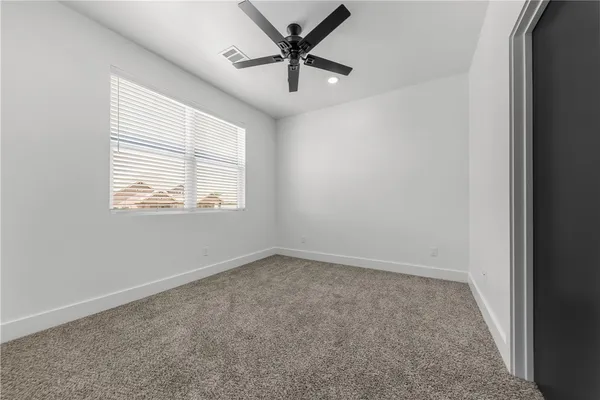 an empty room with a window and a ceiling fan