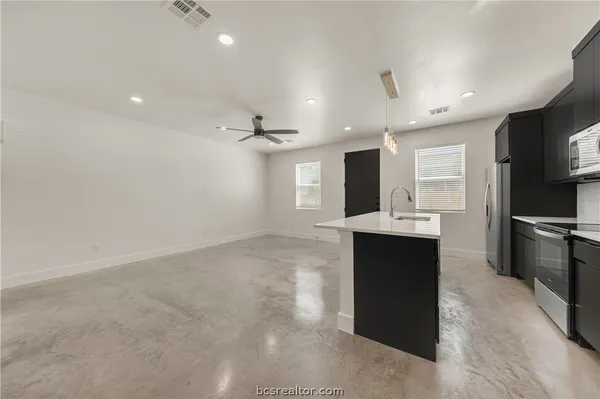 a kitchen with kitchen island a sink stainless steel appliances and cabinets