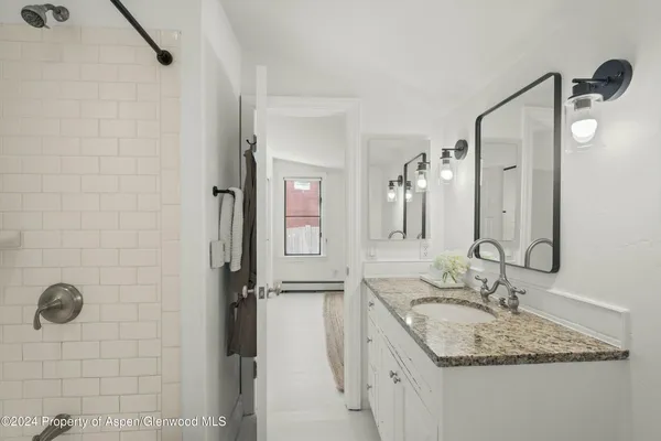 a bathroom with a granite countertop sink a mirror and shower