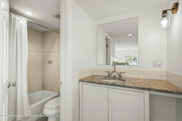 a bathroom with a granite countertop sink toilet and shower