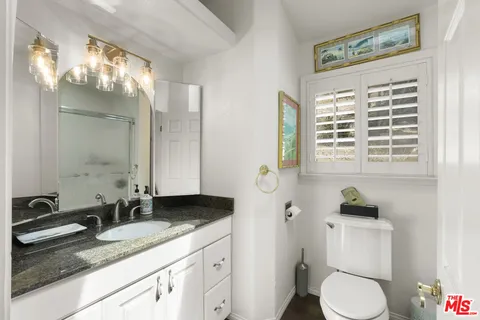 a bathroom with a granite countertop sink toilet and mirror