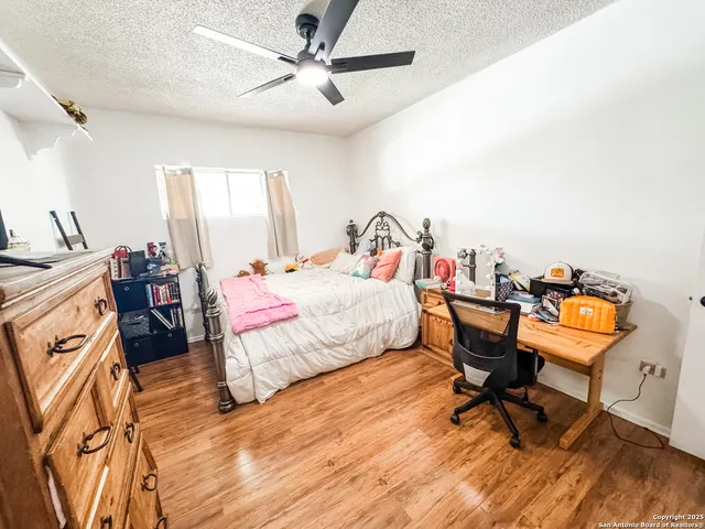 a bedroom with a bed a desk and chair with wooden floor