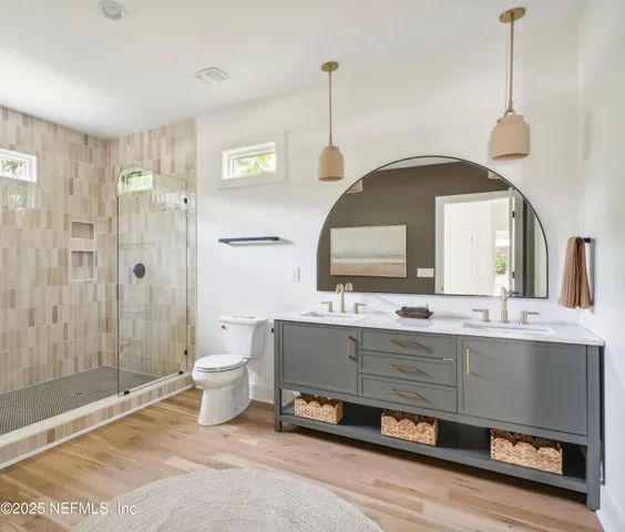 a spacious bathroom with a double vanity sink a large mirror and a shower