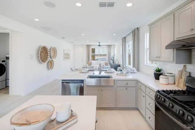 a kitchen with kitchen island granite countertop a sink cabinets and stainless steel appliances