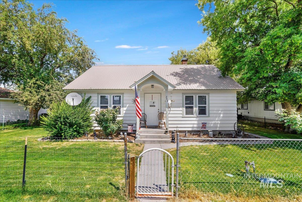 View of front of house featuring a fenced front yard, a gate, a metal roof, and a chimney