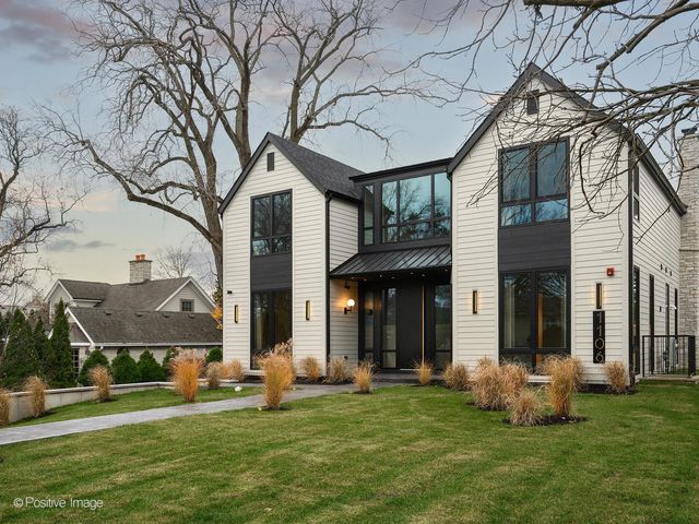 a front view of a house with a garden and trees