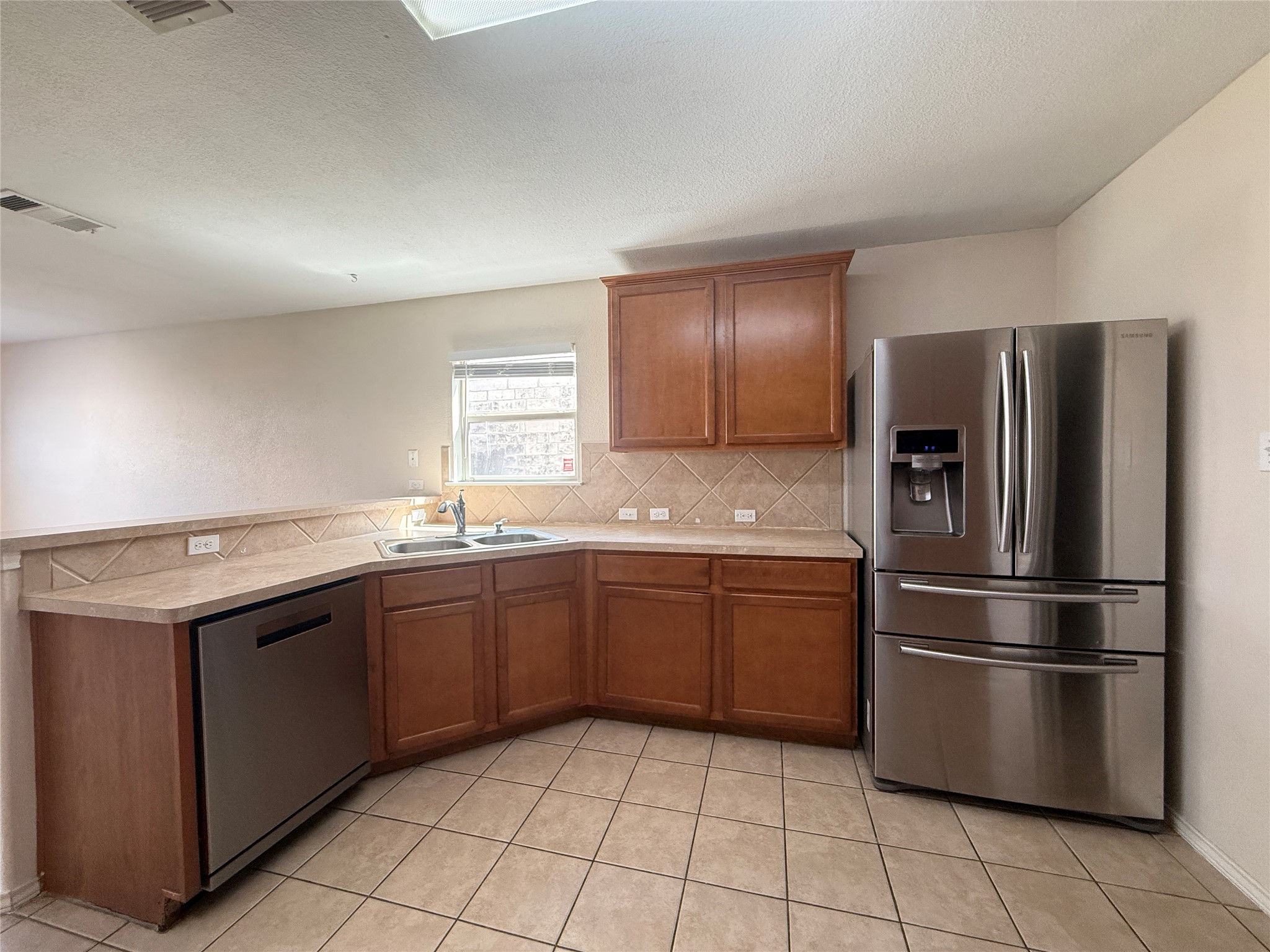 279 Housefinch Loop Leander, TX 78641 - Photo 12 of 30 Kitchen with stainless steel appliances, wood finish cabinets, light countertops, and a textured ceiling