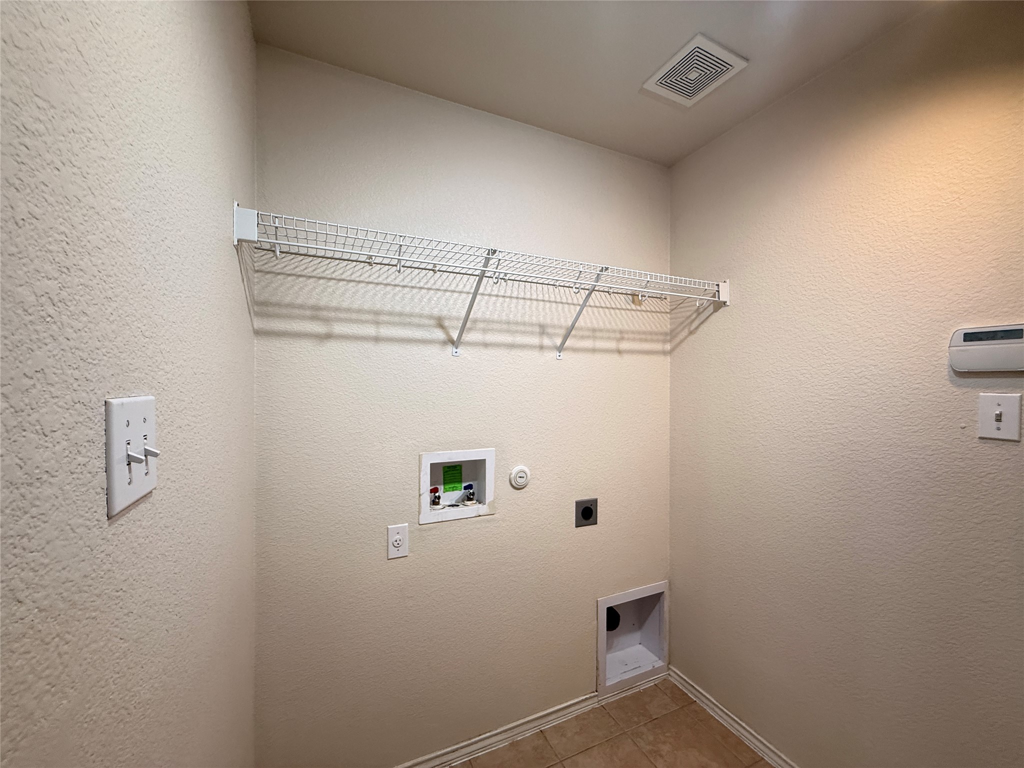 279 Housefinch Loop Leander, TX 78641 - Photo 13 of 30 Laundry area featuring electric dryer hookup, a textured wall, hookup for a washing machine, and light tile patterned flooring