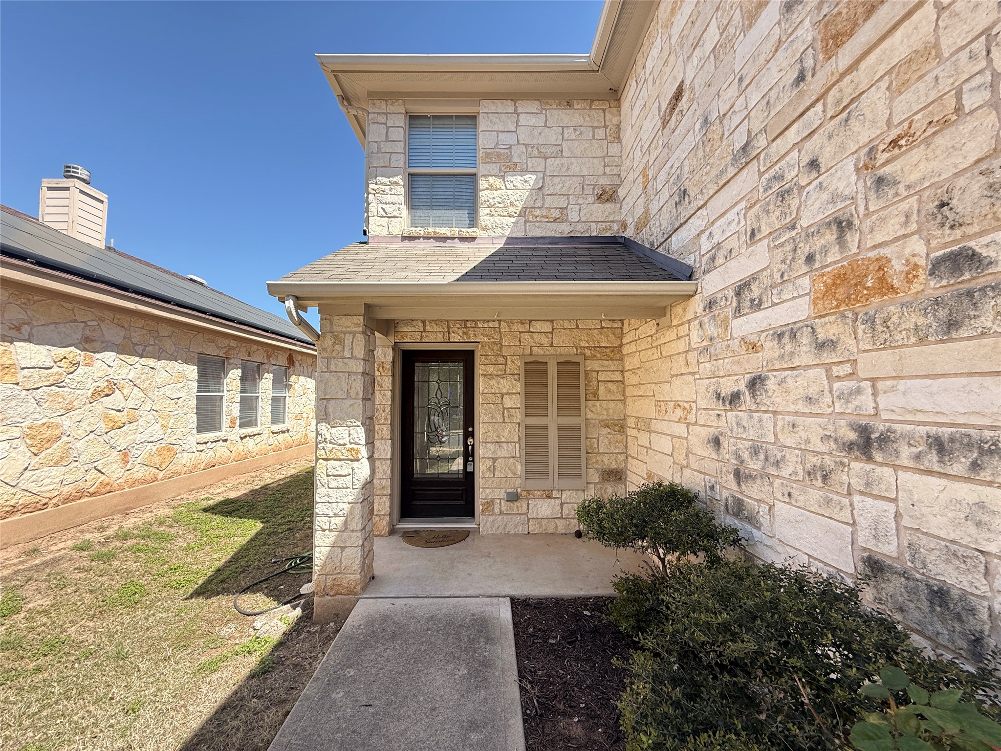 279 Housefinch Loop Leander, TX 78641 - Photo 2 of 30 Doorway to property with stone siding and roof with shingles