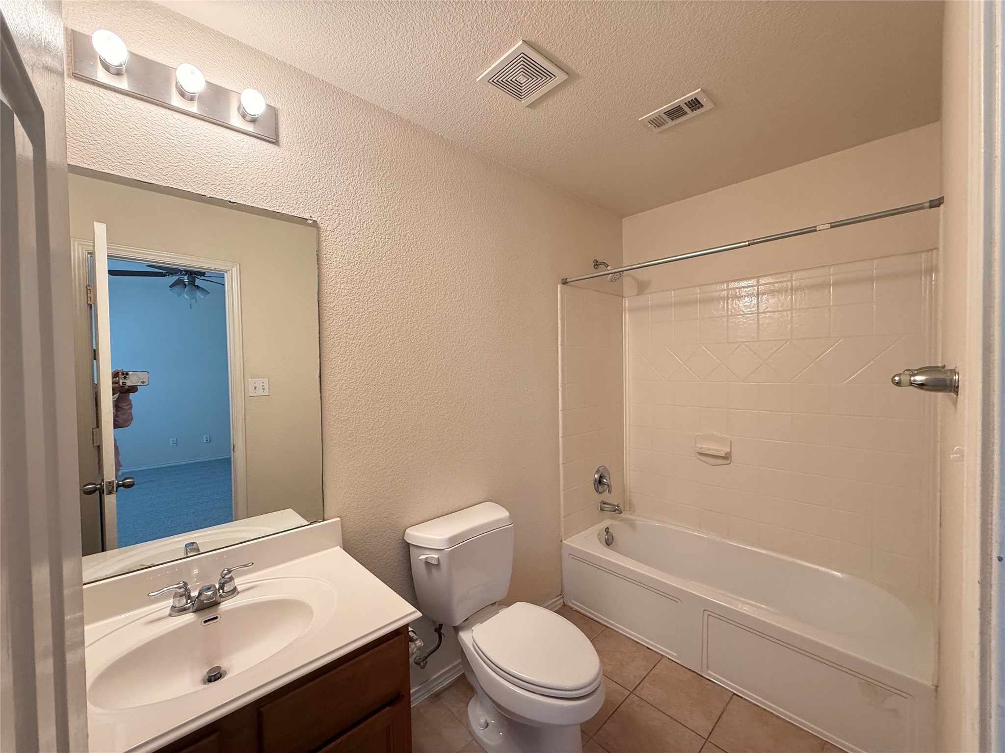 279 Housefinch Loop Leander, TX 78641 - Photo 22 of 30 Full bath featuring a textured wall, vanity, shower combination, a textured ceiling, and light tile patterned floors