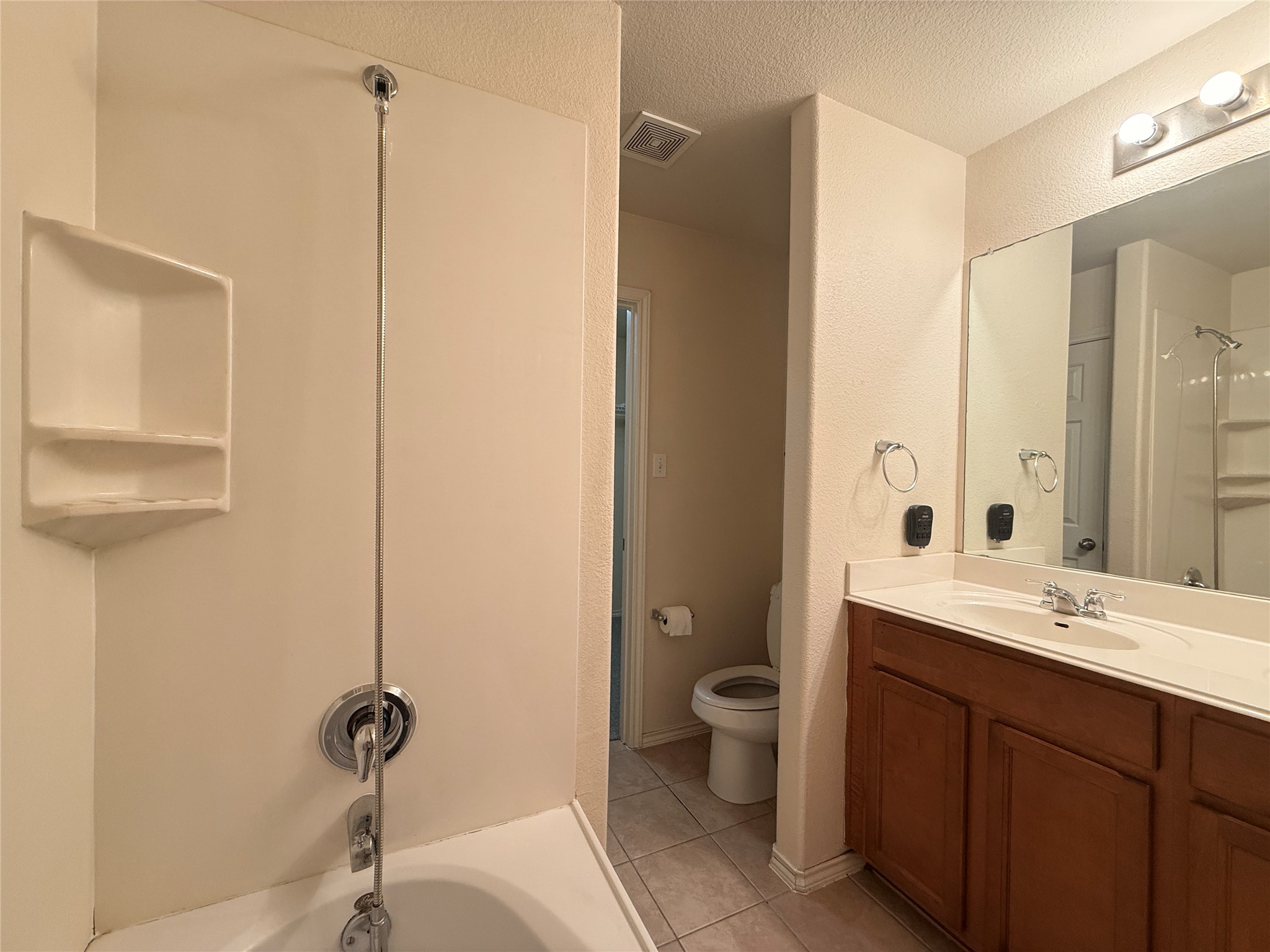 279 Housefinch Loop Leander, TX 78641 - Photo 25 of 30 Bathroom with vanity, a textured wall, a textured ceiling, light tile patterned floors, and shower / washtub combination