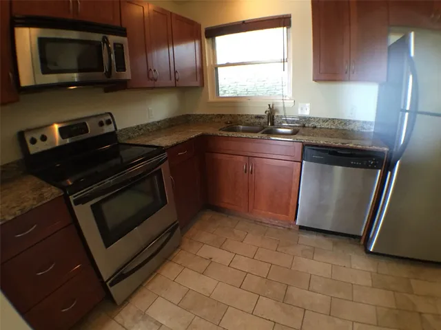 a kitchen with granite countertop a stove a microwave a sink and cabinets