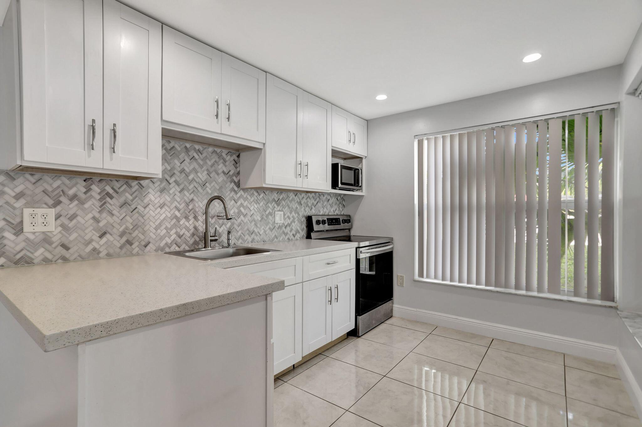 4156 Inverrary Drive, Unit 111 Lauderhill, FL 33319 - Photo 11 of 18 a kitchen with stainless steel appliances granite countertop a sink a stove a refrigerator and cabinets