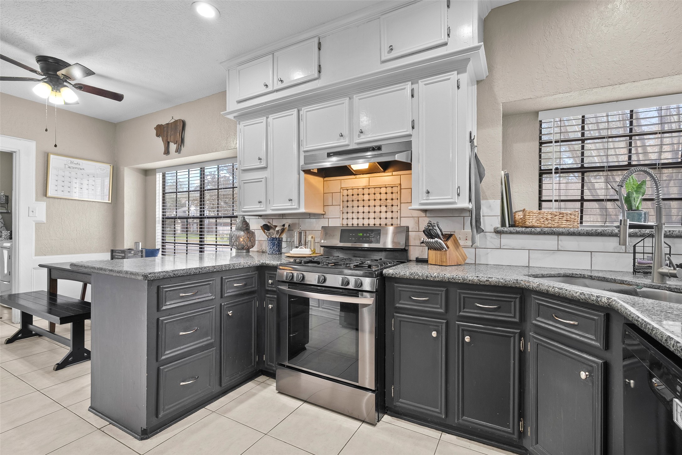41 Windsor Drive Conroe, TX 77304 - Photo 20 of 39 Kitchen featuring white upper cabinetry, contrasting lower cabinets, granite countertops, and a stainless steel gas range.