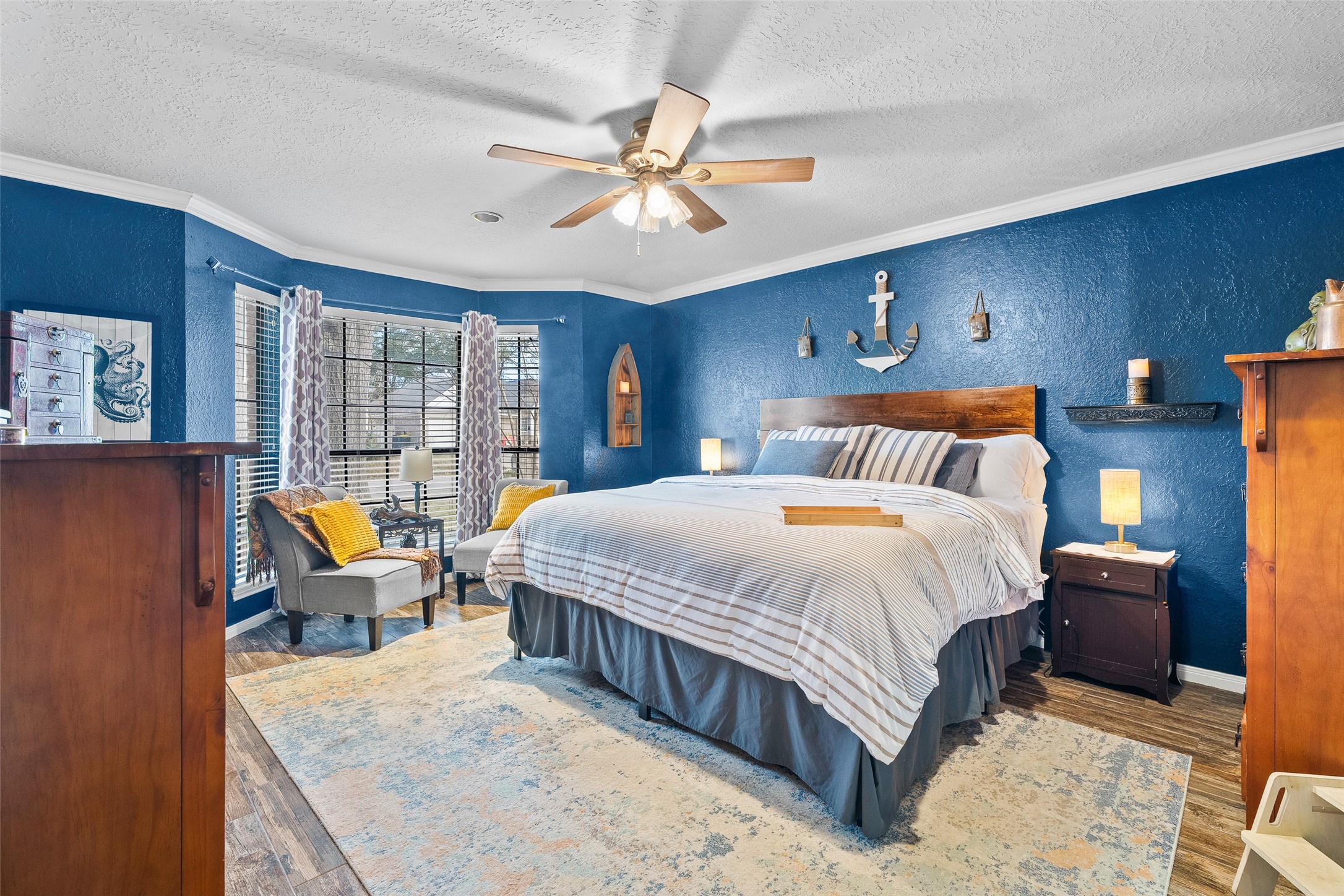 41 Windsor Drive Conroe, TX 77304 - Photo 21 of 39 Primary bedroom with wood-look flooring, crown molding, ceiling fan, and multiple windows providing natural light.