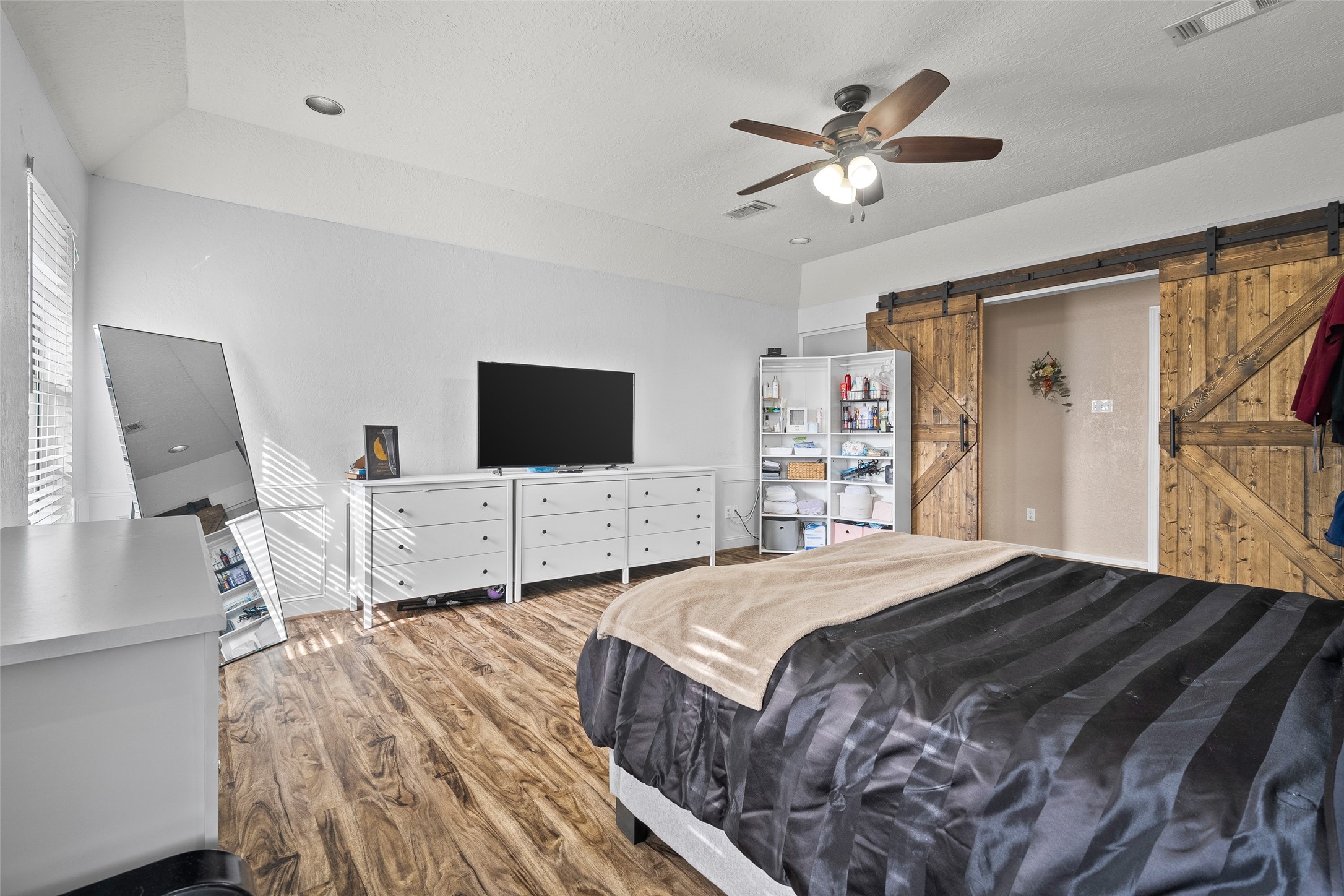 41 Windsor Drive Conroe, TX 77304 - Photo 29 of 39 Additional fifth bedroom originally designed as a game room, now converted into a versatile living space. Features durable wood-style flooring and rustic sliding barn doors, ideal for a bedroom, media room, or bonus space.