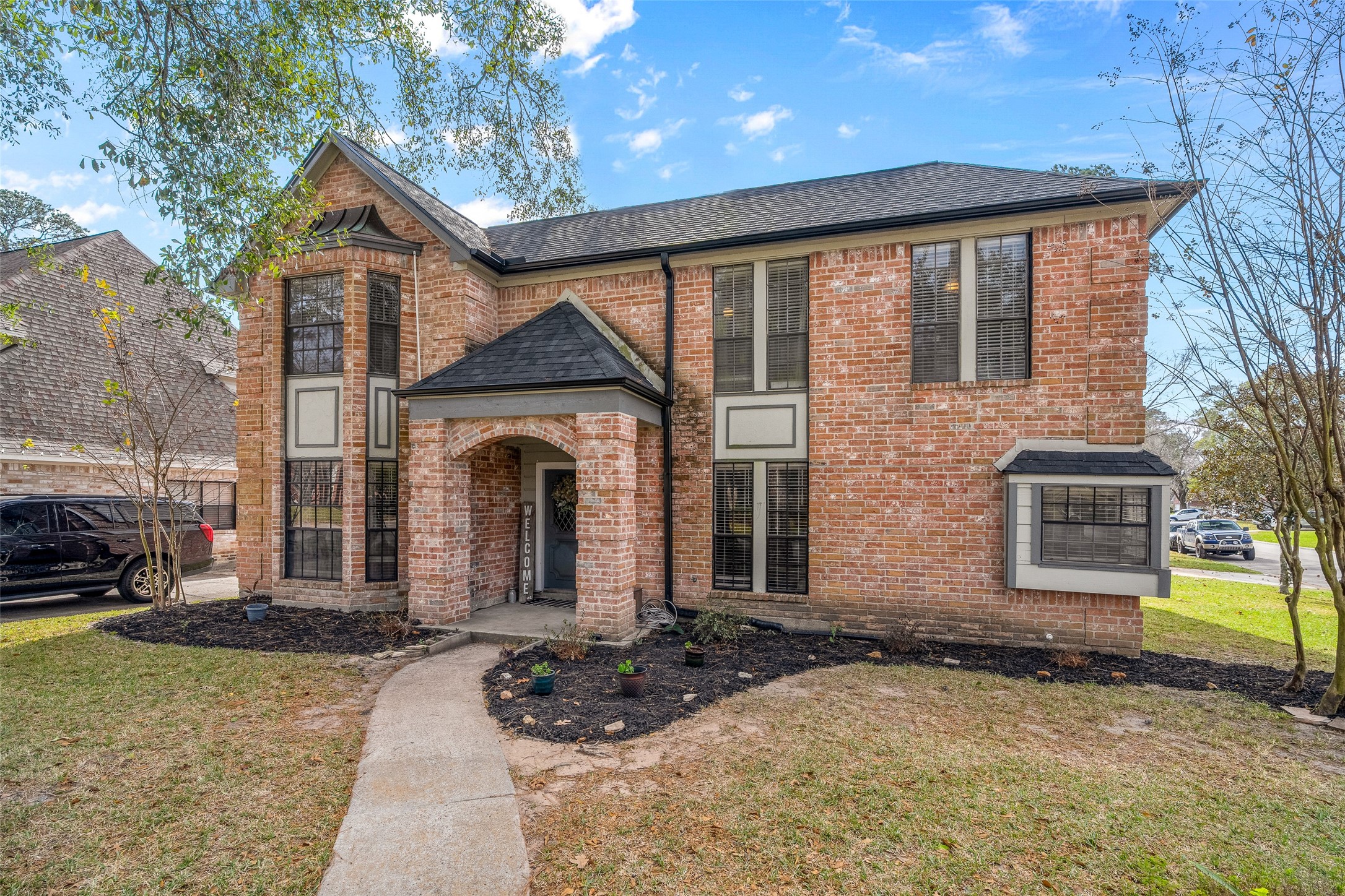 41 Windsor Drive Conroe, TX 77304 - Photo 3 of 39 A second view of the front exterior highlights the home’s classic brick façade, arched covered entry, and recently updated roof.