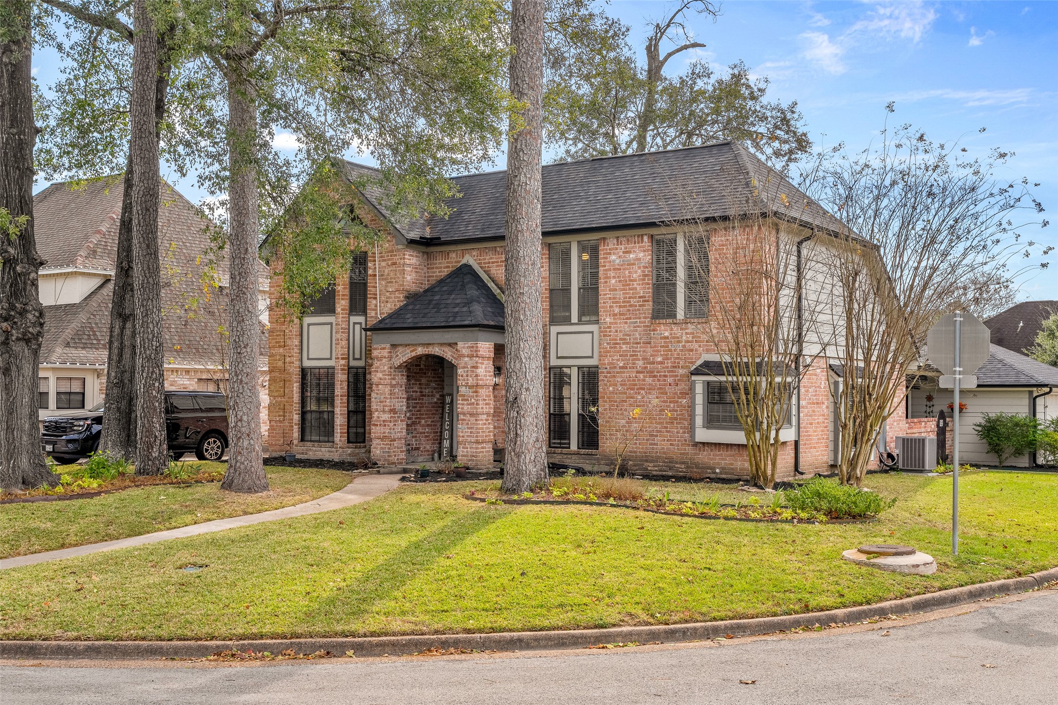 41 Windsor Drive Conroe, TX 77304 - Photo 4 of 39 A wider front view highlights the generous lot, mature trees, and quiet corner-style setting. The classic brick exterior and established landscaping reflect the character of the Rivershire community and the home’s well-maintained condition.