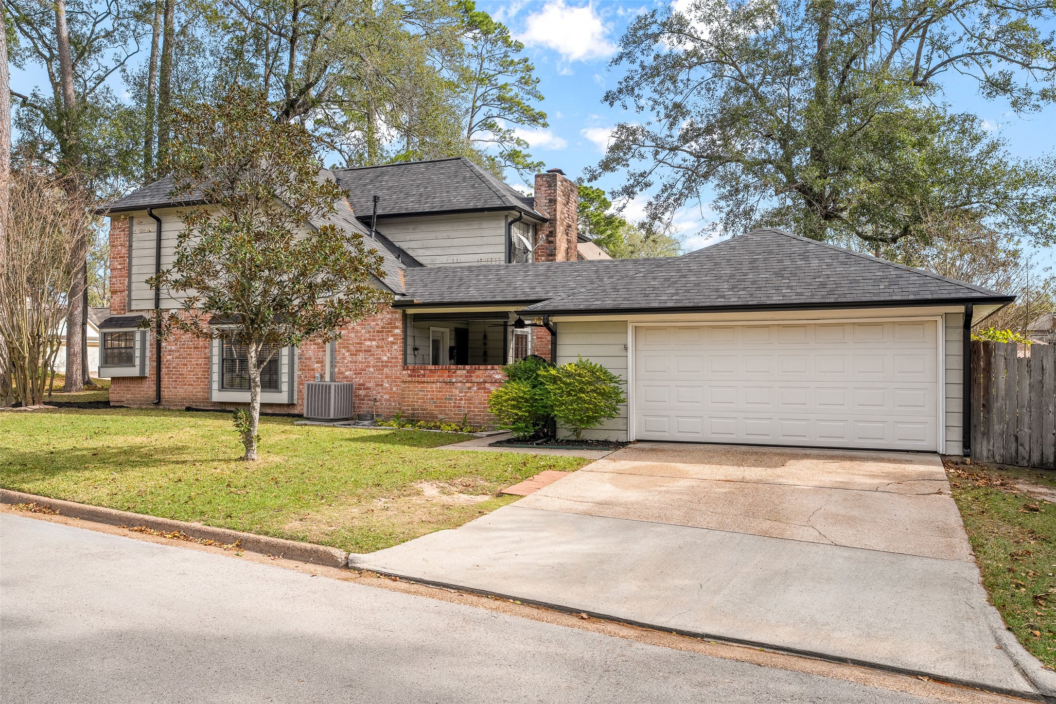 41 Windsor Drive Conroe, TX 77304 - Photo 6 of 39 This side view highlights the attached two-car garage and wide driveway, offering convenient parking and easy access to the home. The angle also shows the home’s depth and spacing, reinforcing the privacy and established feel of the Rivershire neighborhood.