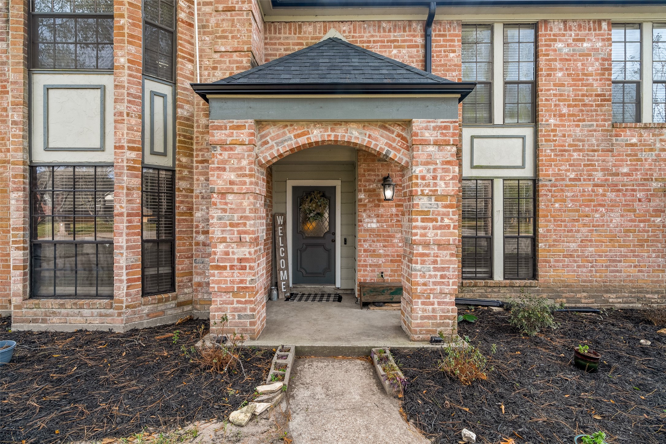 41 Windsor Drive Conroe, TX 77304 - Photo 7 of 39 A closer look at the covered, arched front entry highlights the home’s brick detailing and inviting porch. This protected entry adds everyday convenience and a warm welcome for guests.