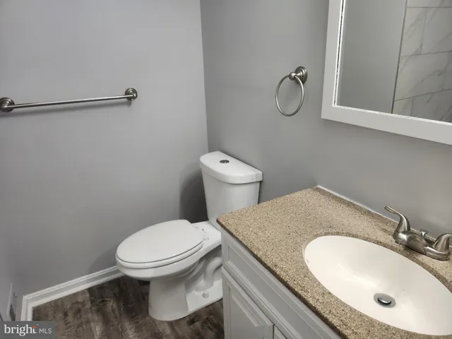 a bathroom with a granite countertop toilet sink and mirror