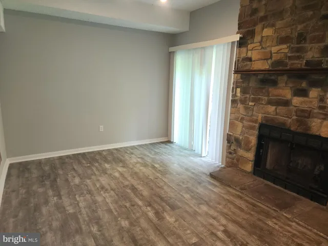 a view of empty room with wooden floor and fireplace