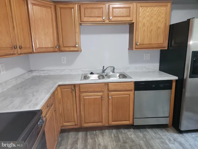 a kitchen with stainless steel appliances granite countertop a sink a stove a refrigerator with grey cabinets