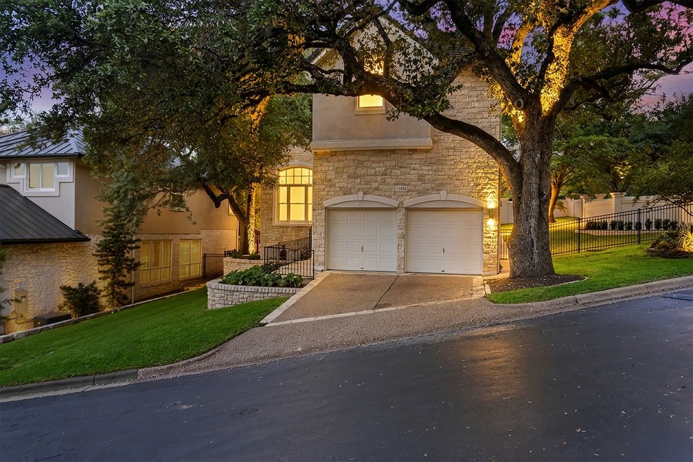 1815 Rue De St Tropez Austin, TX 78746 - Photo 17 of 40 Stone veneer exterior with stucco accents, featuring a two-car garage with white doors