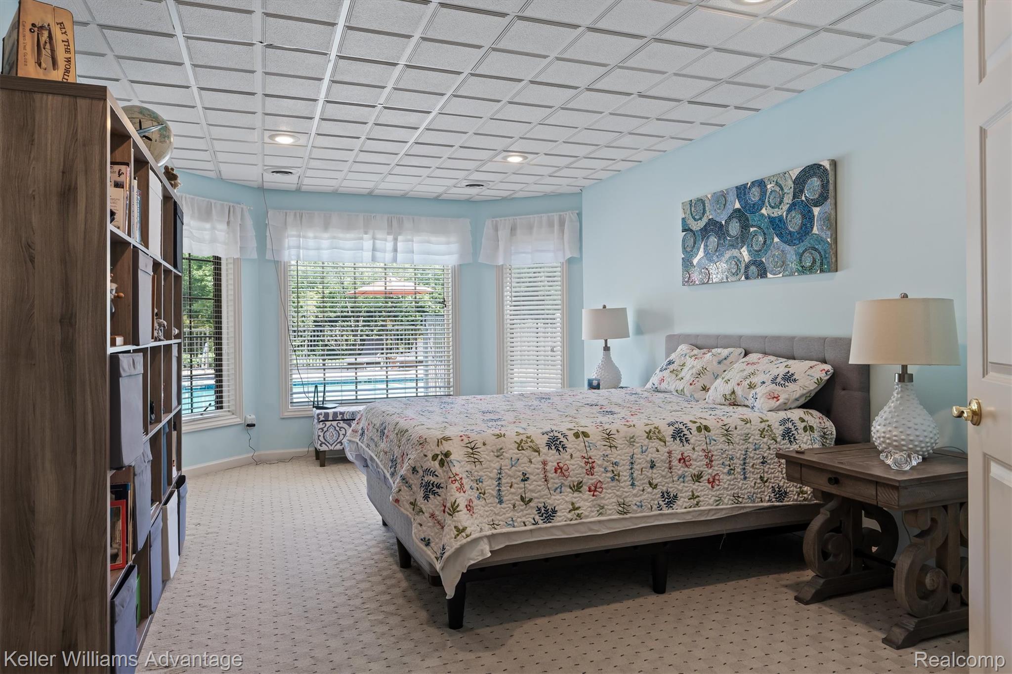 22878 Tree Top Court South Lyon, MI 48178 - Photo 37 of 75 Recessed lighting illuminates a carpeted bedroom featuring a bay window, a visible pool, and a grid-patterned ceiling