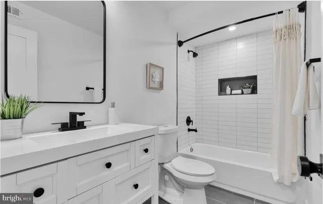 a bathroom with a sink a toilet a mirror a bathtub and shower