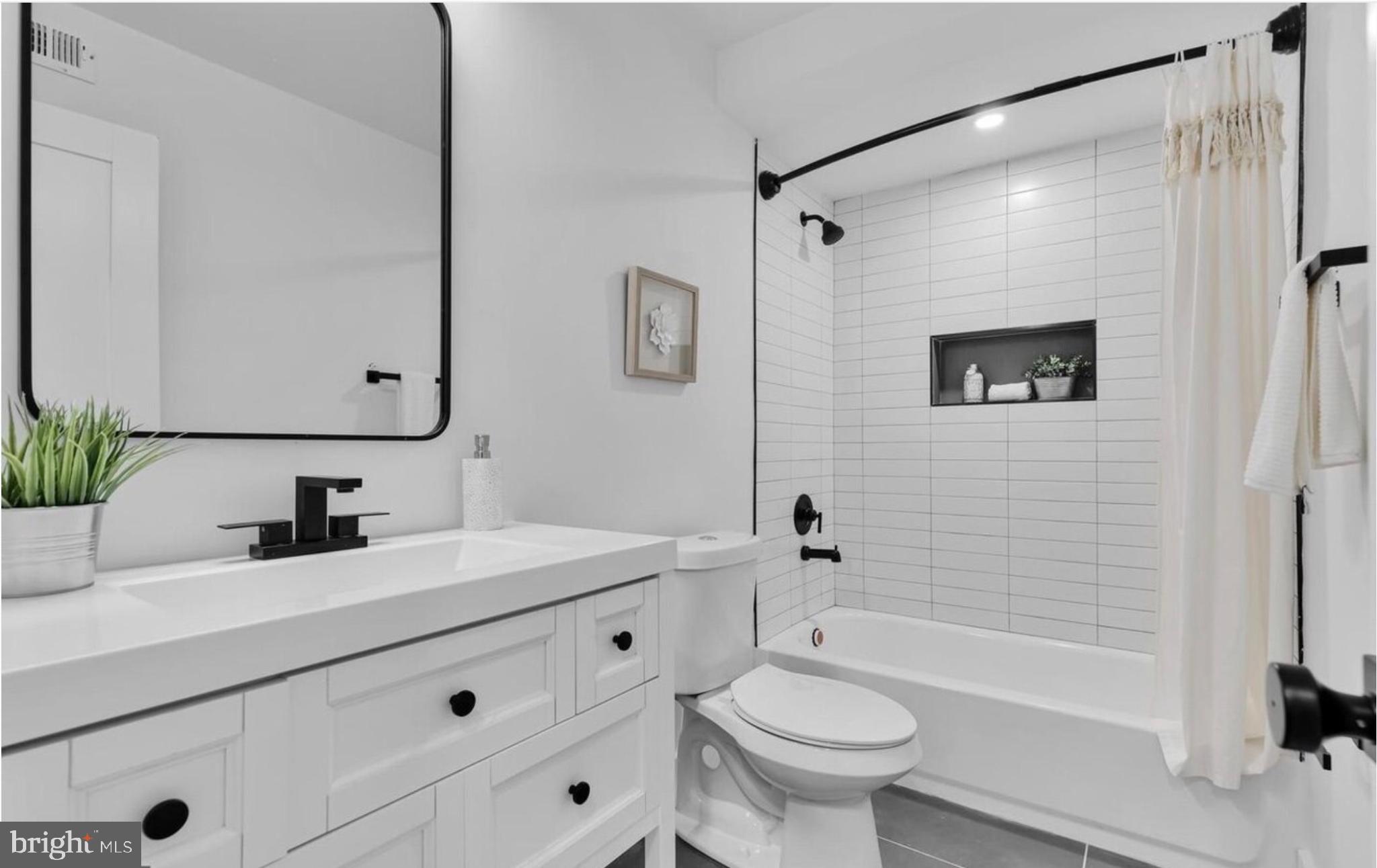 718 6th Street Northeast, Unit 1 Washington, DC 20002 - Photo 17 of 21 a bathroom with a sink a toilet a mirror a bathtub and shower