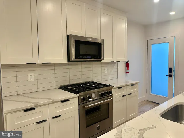 a kitchen with granite countertop white cabinets and stainless steel appliances