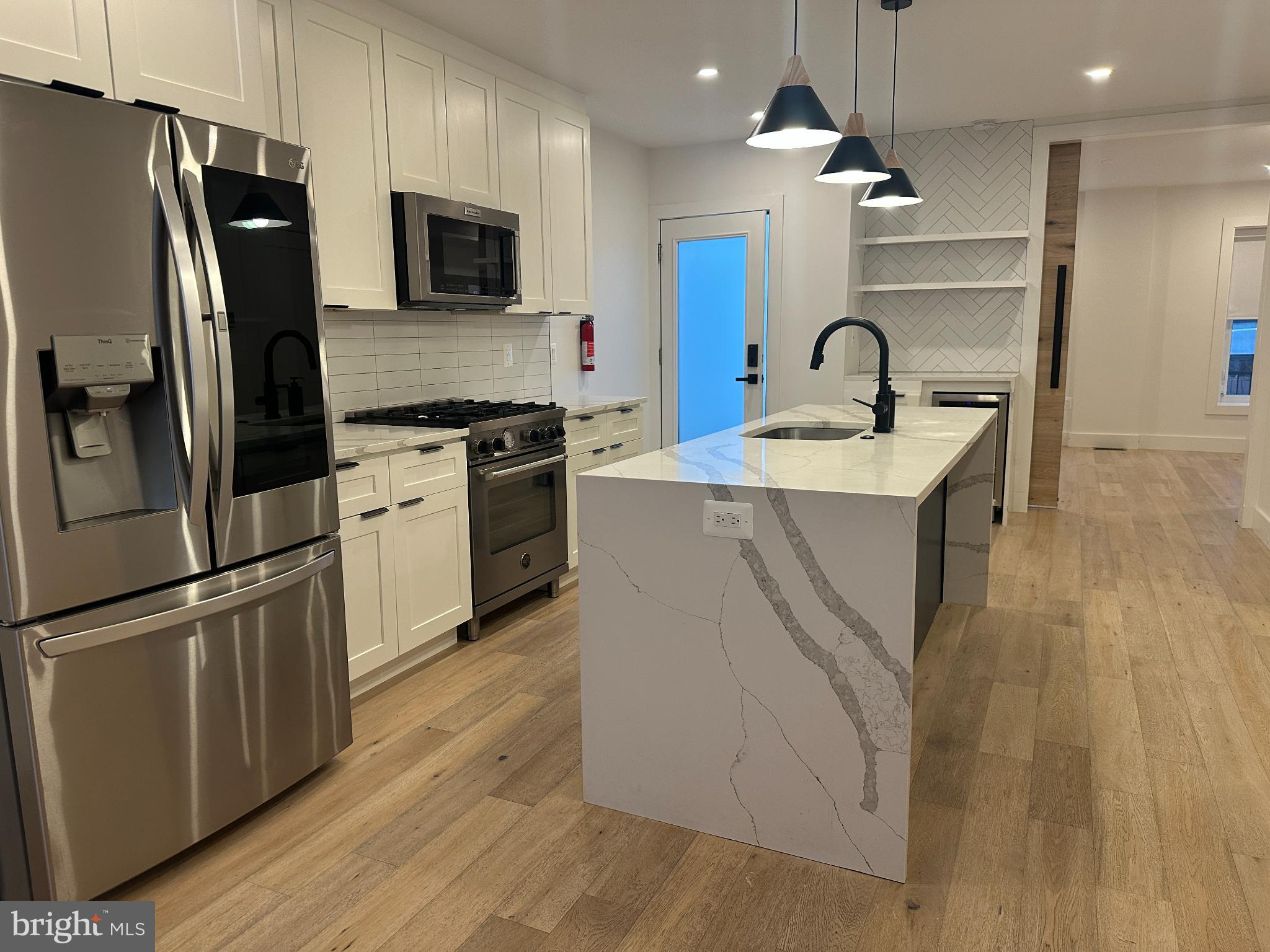 718 6th Street Northeast, Unit 1 Washington, DC 20002 - Photo 7 of 21 a kitchen with stainless steel appliances a refrigerator a sink a stove a microwave and island