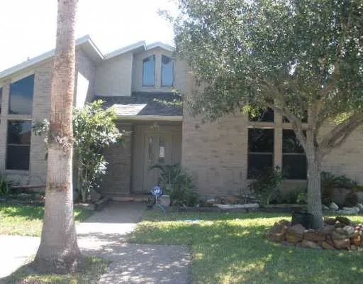 a brick house with a yard and large trees