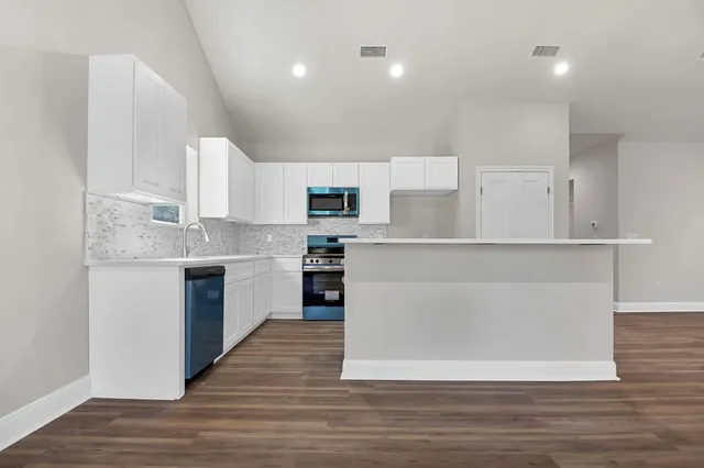 a large kitchen with cabinets wooden floor and stainless steel appliances