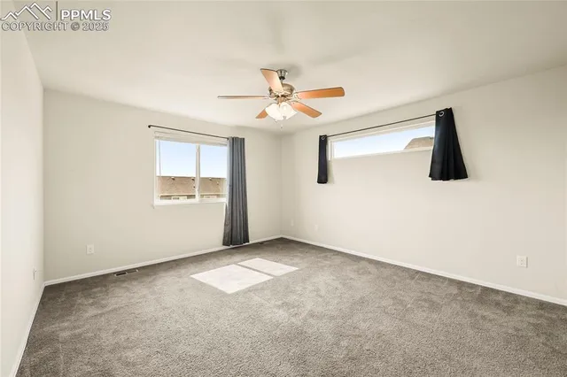an empty room with windows and fan