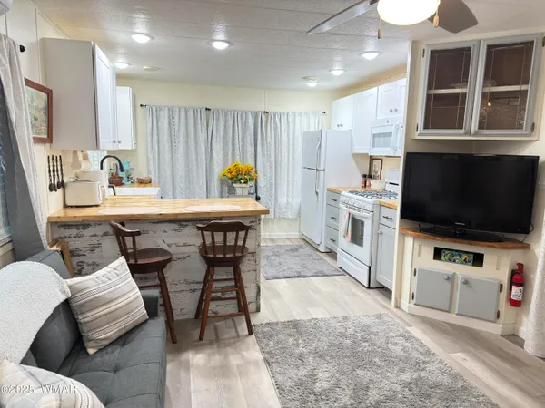 a kitchen with stainless steel appliances kitchen island granite countertop a dining table chairs sink and cabinets