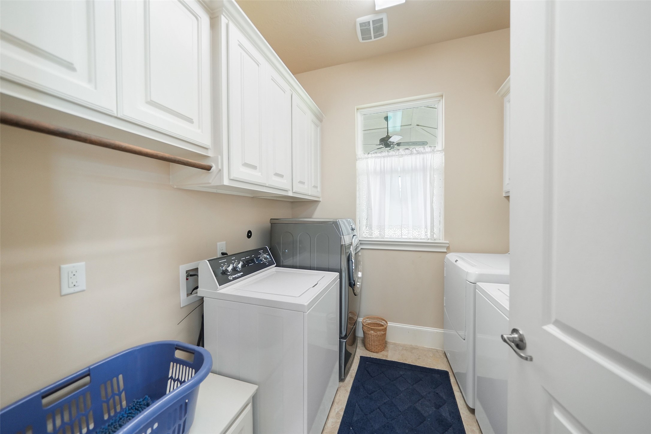 26250 A Riley Road Waller, TX 77484 - Photo 34 of 50 Retreat laundry with dual washers/dryers, upper cabinetry, and window—high-capacity utility room for larger groups or extended stays.