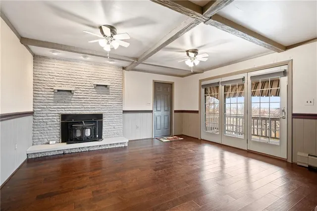 an empty room with wooden floor fireplace and windows