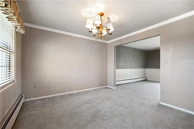 an empty room with a chandelier fan and windows