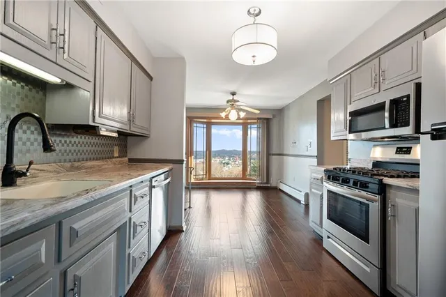 a kitchen with stainless steel appliances granite countertop a stove a sink dishwasher and a microwave oven with wooden floor