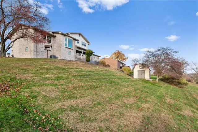 a view of a big house with a big yard and large trees