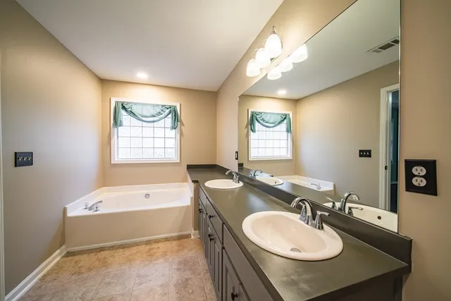 a bathroom with a sink double vanity granite tub and a mirror