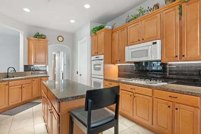 a kitchen with stainless steel appliances granite countertop a stove top oven a sink dishwasher and cabinets with wooden floor