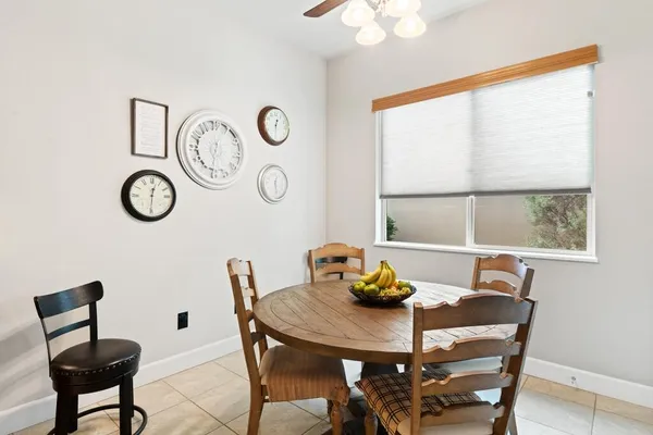 a view of a dining room that has a table and a chair with a bookshelf next to a window
