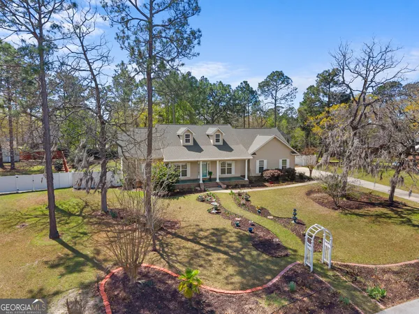 a view of a house with large trees and a yard