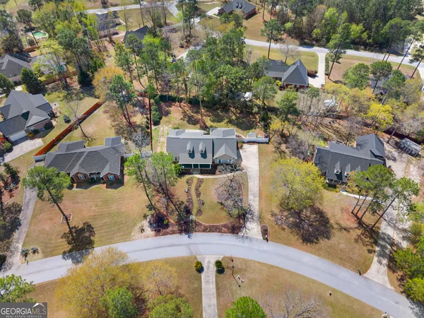 an aerial view of a house with a swimming pool and large trees