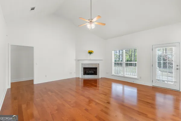 a view of a livingroom with a fireplace a ceiling fan and wooden floor