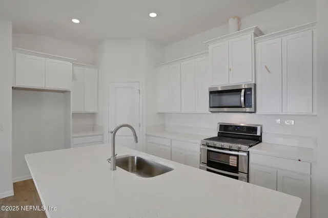 a view of kitchen with stainless steel appliances granite countertop a sink stove and refrigerator