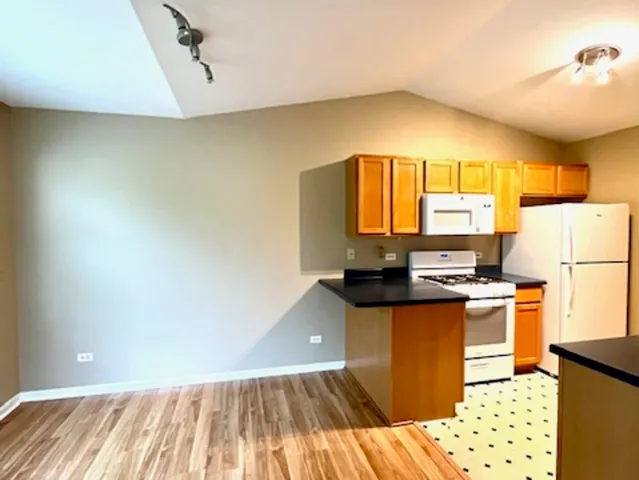 a kitchen with granite countertop a stove a sink dishwasher and a refrigerator with wooden floor